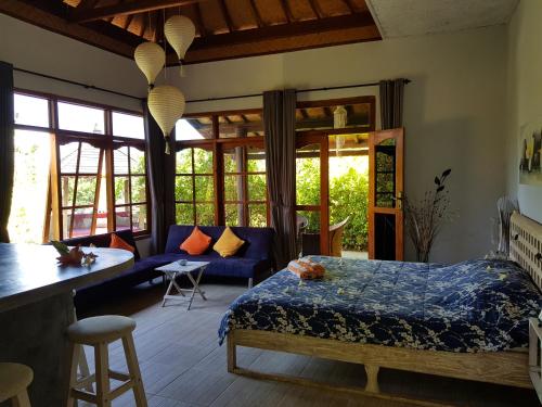 a bedroom with a blue bed and a couch at Villa Lumbalumba in Lovina