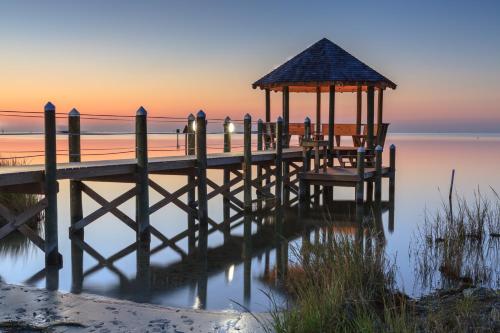 a pier with a gazebo on the water at sunset at 57310 Eagle Pass Rd Home in Hatteras