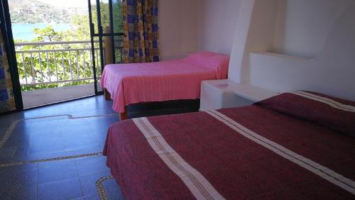 a hotel room with two beds and a balcony at Pie de Playa la Ropa in Zihuatanejo