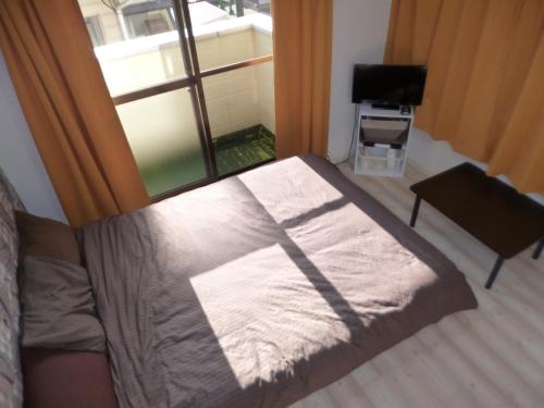 Bett in einem Zimmer mit Fenster in der Unterkunft THE MICKEY CARLTON Ohashi 201 in Shiobaru