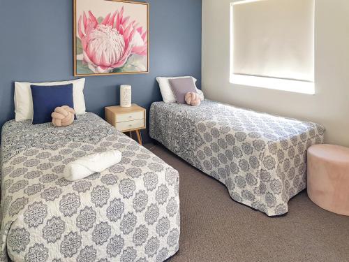 a bedroom with two beds and a picture on the wall at Kings Way Apartments in Caloundra