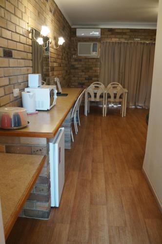 a kitchen with a counter with a microwave and chairs at Magdala Motor Lodge & Lakeside Restaurant in Stawell