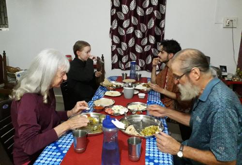 a group of people sitting around a table eating food at Tadoba Homestay Cottage in Chandrapur