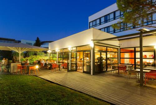a building with a deck with tables and chairs at Holiday Inn - Strasbourg - Nord by IHG in Schiltigheim