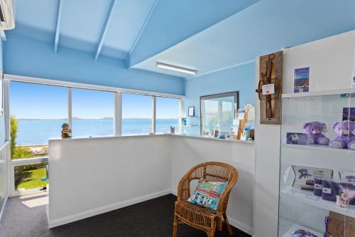 Swansea Motor Inn Tasmania في سوانسي: غرفة مع منضدة مع كرسي ونوافذ