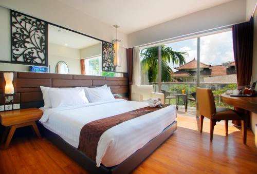 um quarto com uma cama, uma secretária e uma janela em The Lerina Hotel Nusa Dua em Nusa Dua