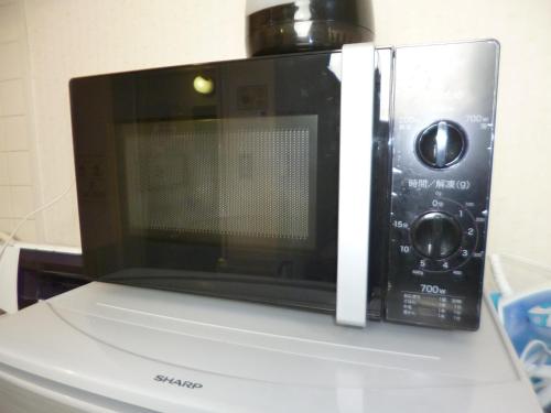 a microwave oven sitting on top of a refrigerator at ザ ミッキー カールトン 井尻 101 in Fukuoka