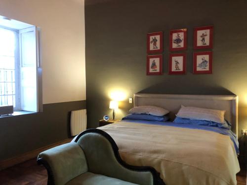 a bedroom with a bed with a chair and pictures on the wall at Casona Lo Aguirre , Hospedaje de Temporada Cálidas in Talagante