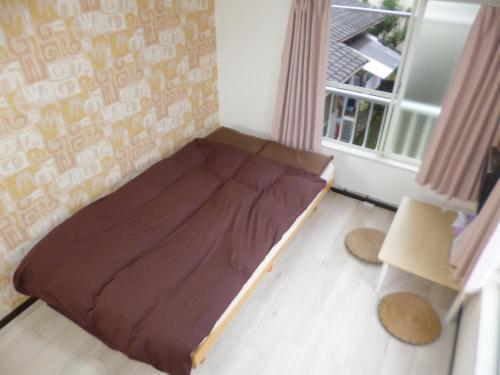 ein kleines Bett in einem Zimmer mit Fenster in der Unterkunft ザ ミッキー カールトン 井尻 203 in Shiobaru