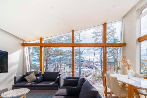 a living room with a table and a large window at Alpinarc Chalet by Hakuba White Fox Company in Hakuba