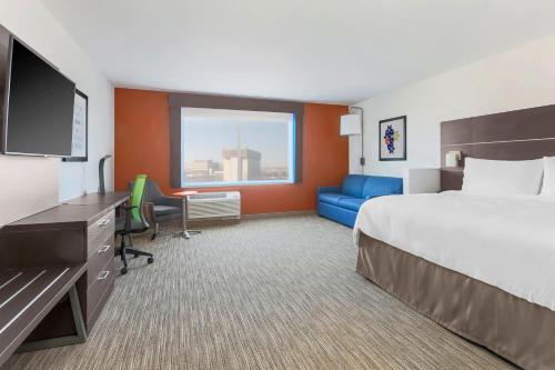 デスプレーンズにあるHoliday Inn Express & Suites Chicago O'Hare Airport, an IHG Hotelのベッド、デスク、テレビが備わるホテルルームです。