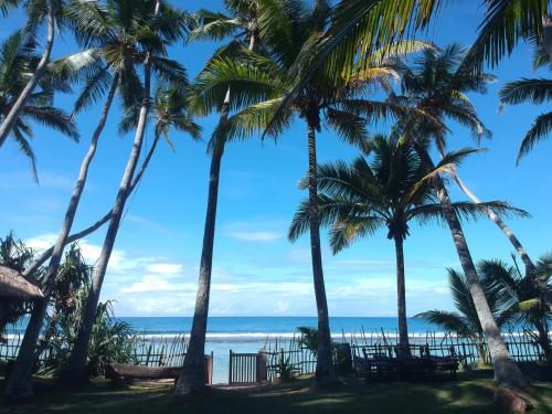 a view of the ocean from a beach with palm trees at Galawatta Beach Resort in Unawatuna