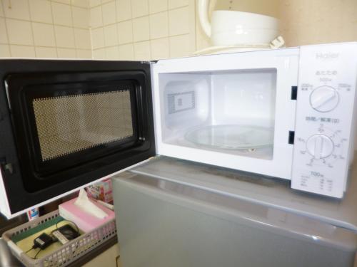 a microwave sitting on top of a refrigerator at ザ ミッキー カールトン 井尻 202 in Shiobaru