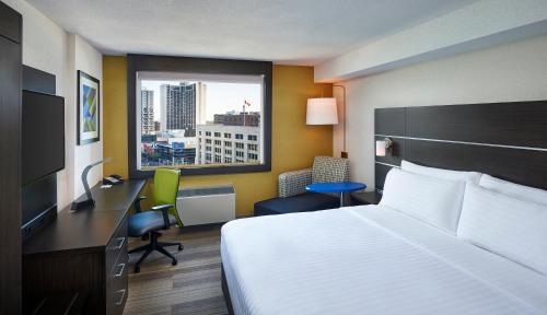 a hotel room with a bed and a desk and a window at Holiday Inn Express Windsor Waterfront by IHG in Windsor