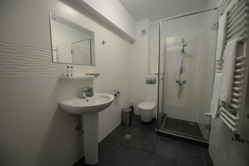 a white bathroom with a sink and a shower at PENSIUNEA ARINAS in Vatra Dornei