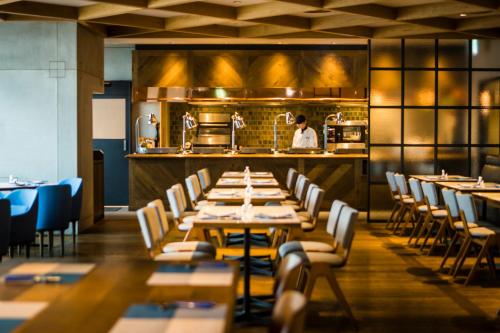 a dining room with tables and a chef in the kitchen at Kawasaki King Skyfront Tokyu REI Hotel in Kawasaki