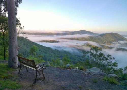 a bench sitting on top of a hill overlooking a foggy valley at Valley View Luxury Retreat in Vacy
