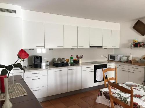 a white kitchen with white cabinets and a table at B&B RONCHI in Castelrotto