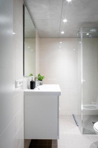 a white bathroom with a sink and a shower at Studio Puuur in Zandvoort
