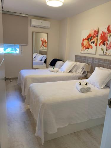 um quarto de hotel com três camas com lençóis brancos em Luxury Apartamento Minerva Júpiter em Benalmádena