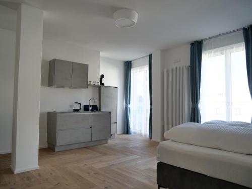 a white bedroom with a bed and a dresser at Apartments Sabine G in Merano