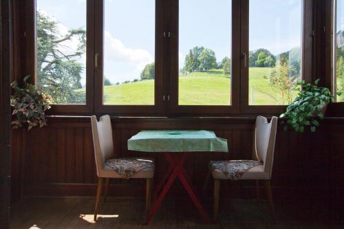 a table and two chairs in a room with windows at Villa Presolana in Castione della Presolana