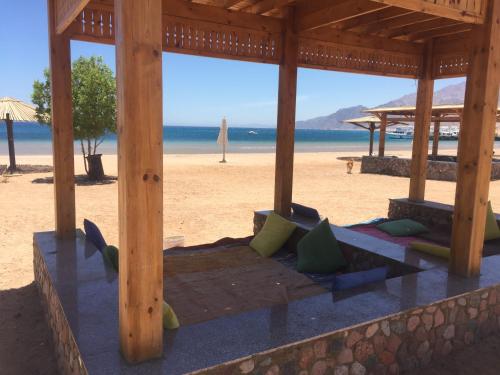 a wooden pavilion on a beach with the ocean at Deluxe Seahorse Apartment - Lagoon Villa in Dahab