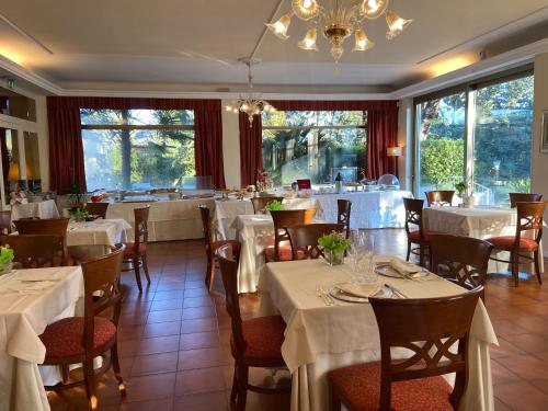 un ristorante con tavoli e sedie bianchi e un lampadario a braccio di Hotel Villa Pigna ad Ascoli Piceno