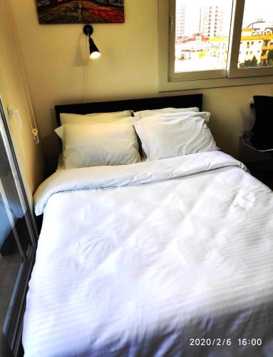 a bed with white sheets and pillows in a room at RiX Studio Park Famagusta Contactless Check In & Check Out in Mağusa