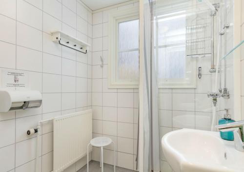 a white bathroom with a sink and a window at Malmgårdens vandrarhem B&B in Strängnäs