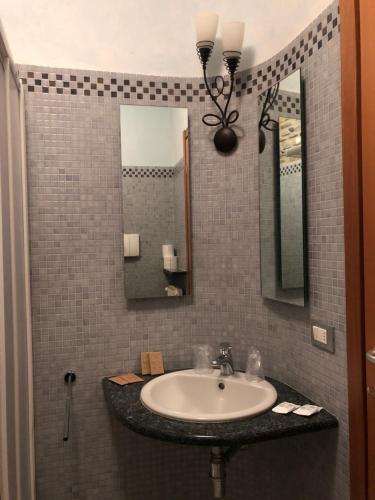 ein Bad mit einem Waschbecken und einem Spiegel in der Unterkunft Da Nando Antica Osteria Hotel in Godi