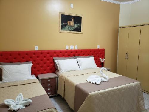 a bedroom with two beds and a red headboard at Hotel Litoral Sul in Coruripe