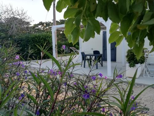 a small white house with a table and a chair at Giardino D'Oriente in Otranto