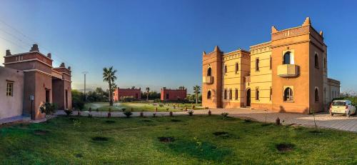 a large building with a grass yard in front of it at Villa Diaf Johanne in Aït Ourir