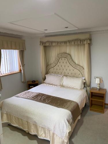 um quarto com uma cama grande e uma grande cabeceira. em Bessemer Hotel em Merthyr Tydfil