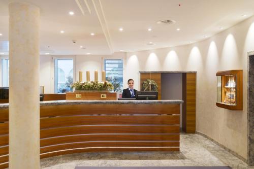 a man in a suit sitting at a counter in a lobby at Glärnischhof by TRINITY in Zürich