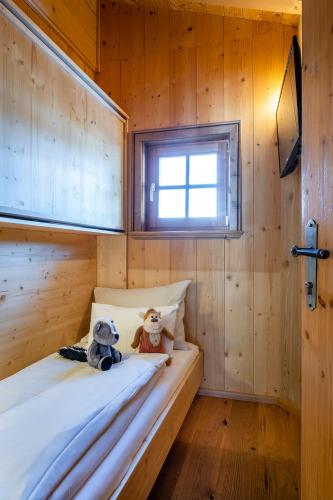 two teddy bears sitting on a bed in a wooden room at Almdorf Almlust in Flachau