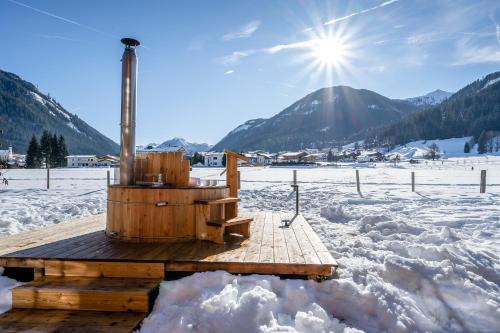 a hot tub on a wooden deck in the snow at Almdorf Almlust in Flachau
