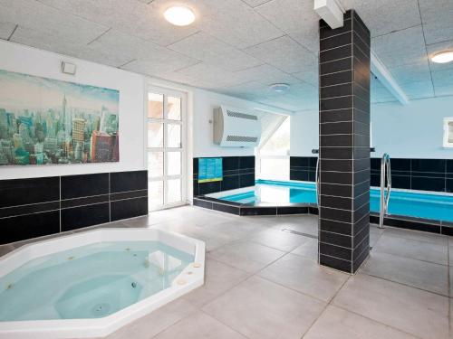 a large bathroom with a tub and a swimming pool at 21 person holiday home in Bl vand in Blåvand