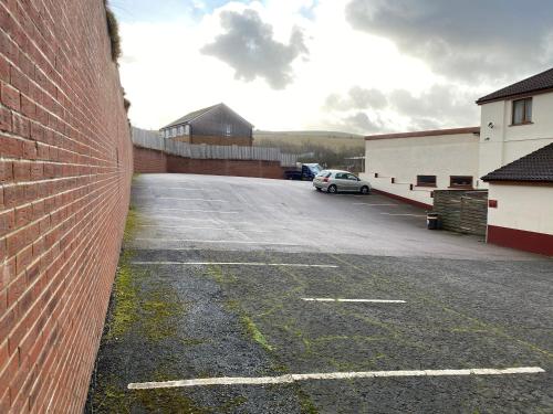 a car parked in a parking lot next to a brick wall at Bessemer Hotel in Merthyr Tydfil