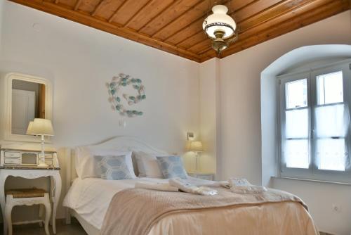 a bedroom with a large white bed with a window at Hydra's Pearl - White Pearl in Hydra