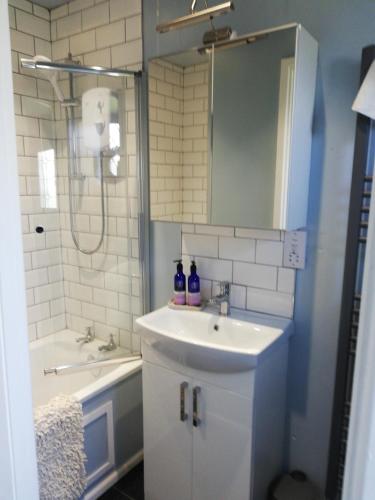 La salle de bains est pourvue d'un lavabo, d'une douche et d'une baignoire. dans l'établissement Little Cosy Cwtsh, à Pontyclun