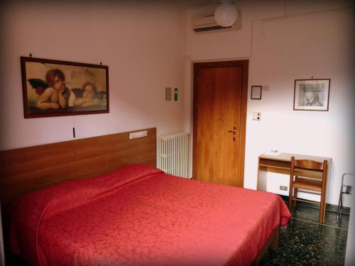 a bedroom with a red bed and a desk at Hotel Triestina in Noli