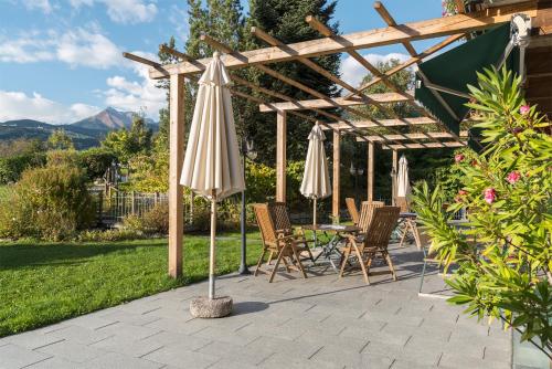a patio with umbrellas and chairs under a pergola at Landhotel Gasthof Zum Löwen in Rodengo
