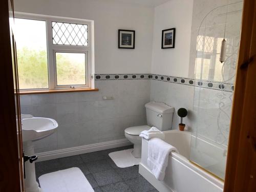 a bathroom with a tub and a toilet and a sink at Atlantic View House in Killybegs