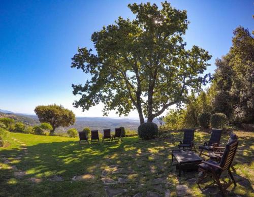 a group of chairs sitting in the grass under a tree at Domaine du Bois d'Amont in Cabris
