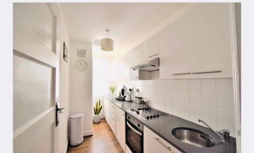 a white kitchen with a sink and a counter at Super location 1min from metro 10min from Camden in London