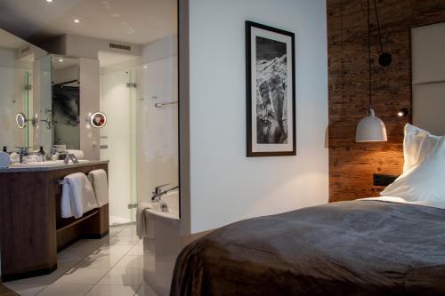 a bedroom with a bed and a bathroom with a tub at Walliserhof Grand-Hotel & Spa Relais & Châteaux in Saas-Fee