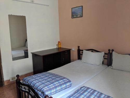 a bedroom with two beds and a dresser and a mirror at REFLECTIONS Guest House in Ooty