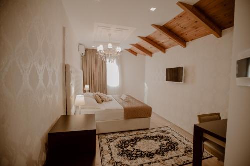 a bedroom with a bed and a table and a chandelier at Green House Hotel & Restaurant in Tirana